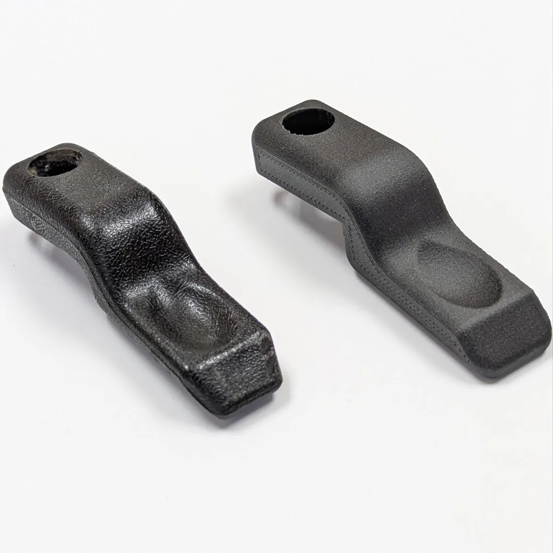 Gray 3D-printed handle parts with metal threaded inserts, laid in a row.